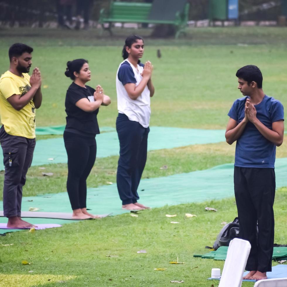 New Delhi, India, June 18 2022 - Group Yoga exercise class Surya Namaskar for people of different age in Lodhi Garden, International Yoga Day, Big group of adults attending a yoga class in park photo