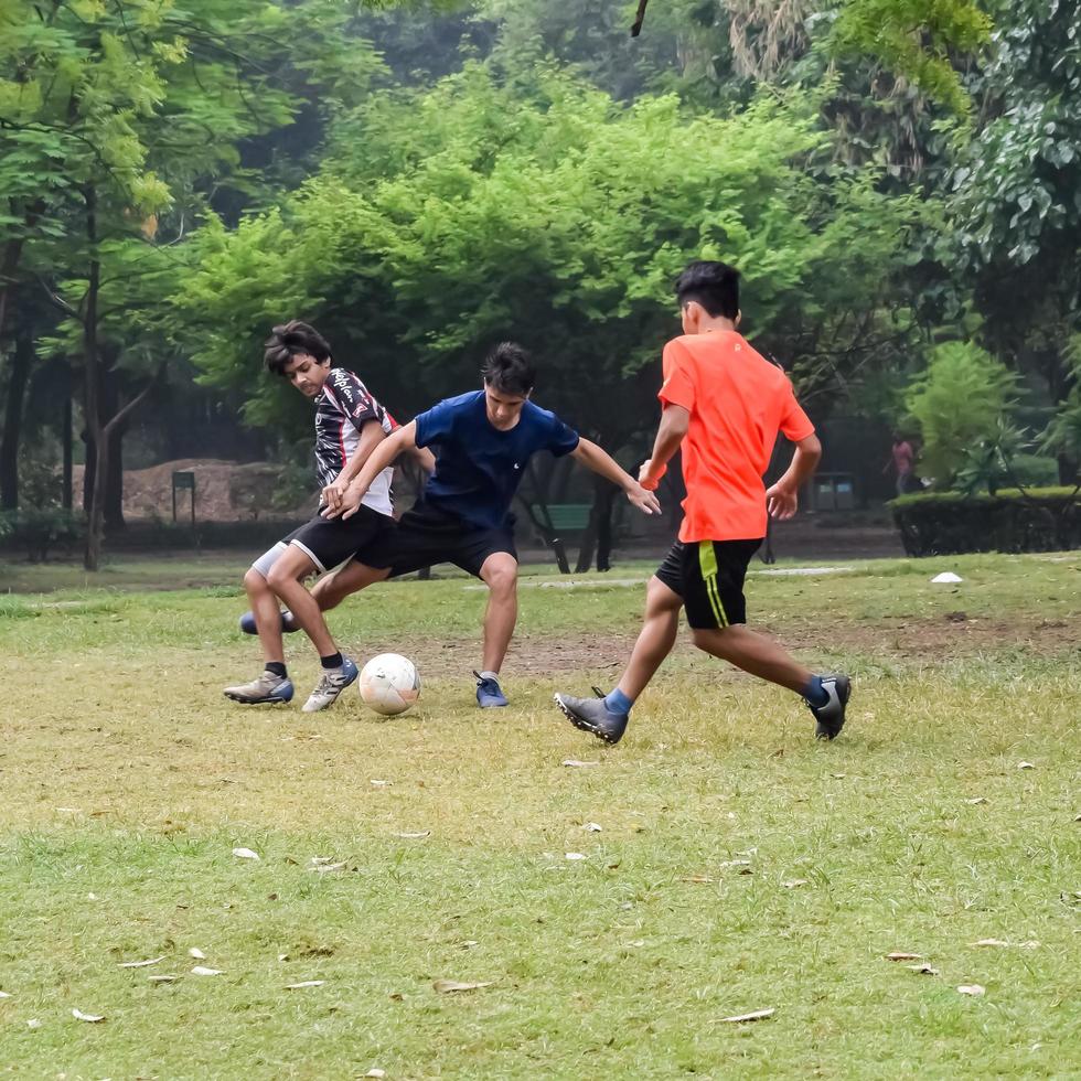 New Delhi, India - July 01 2018 -Footballers of local football team during game in regional Derby championship on a bad football pitch. Hot moment of football match on grass green field of the stadium photo