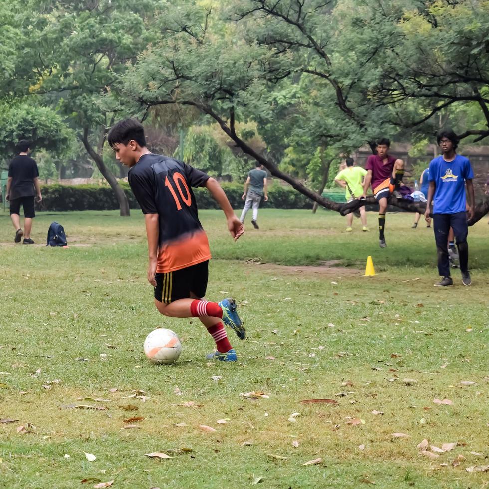 New Delhi, India - July 01 2018 -Footballers of local football team during game in regional Derby championship on a bad football pitch. Hot moment of football match on grass green field of the stadium photo