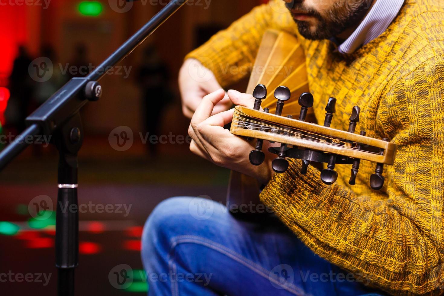 manos de un músico con un traje folclórico tocando en domra tremolo. manos del músico en movimiento. enfoque selectivo. foto