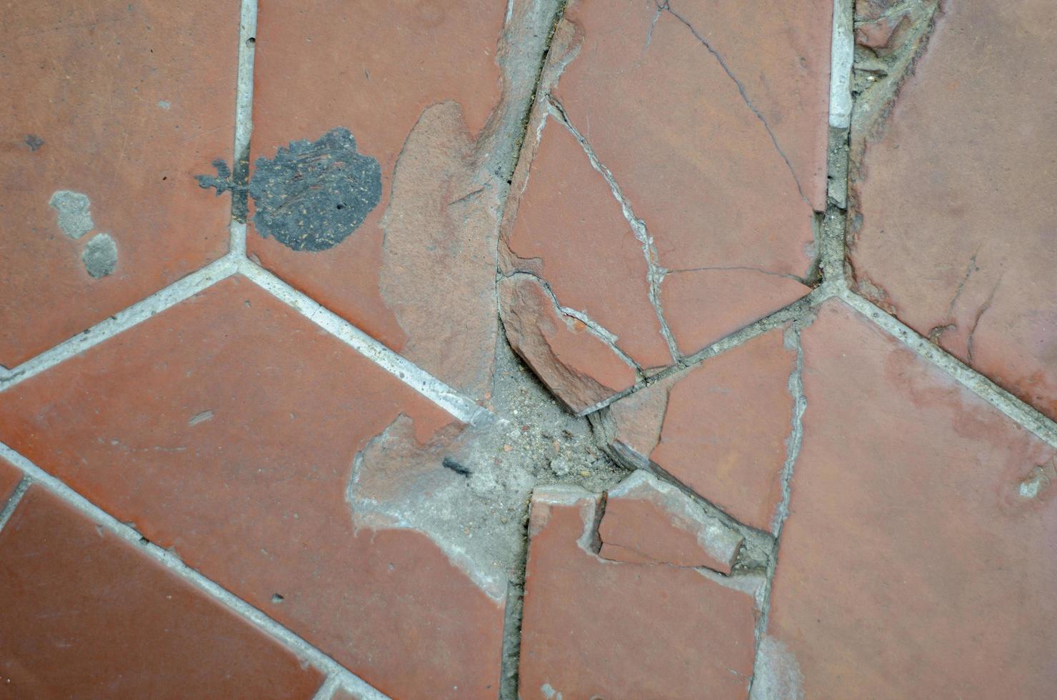 The road surface or walkway is made of broken and damaged orange bricks. photo