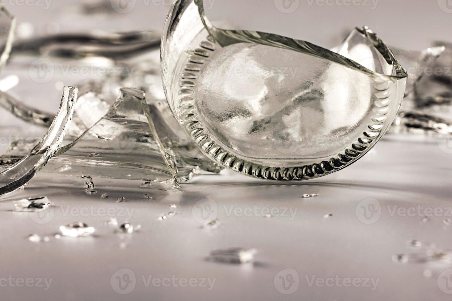 A glass bottle broken into many fragments on a gray background. photo