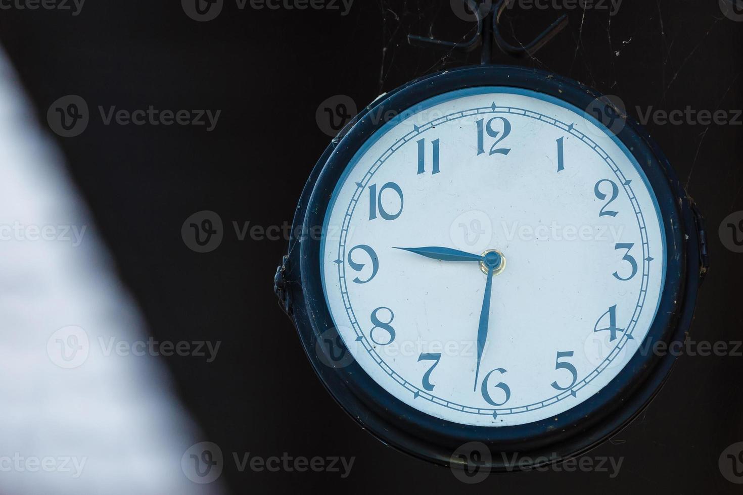 Horas antiguas, reloj de 9.30 horas en una mesa de madera en el jardín verde a las 00:00 foto