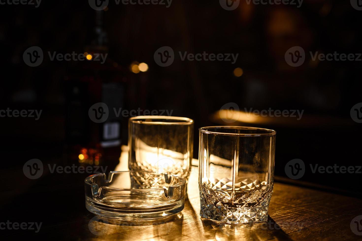 vasos de whisky con cigarro humeante y cubitos de hielo en la mesa de madera foto