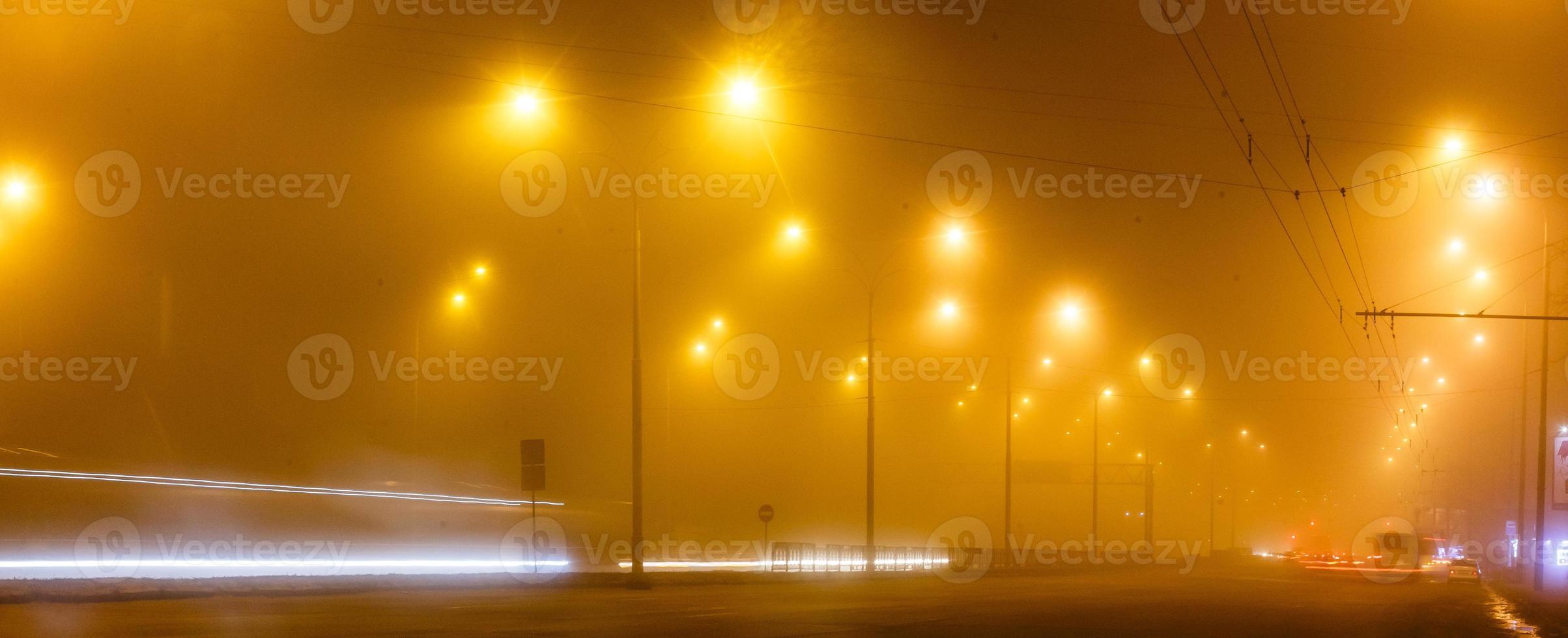 City night lights road bridge with the lights and moving car in the fog after rain view from photo