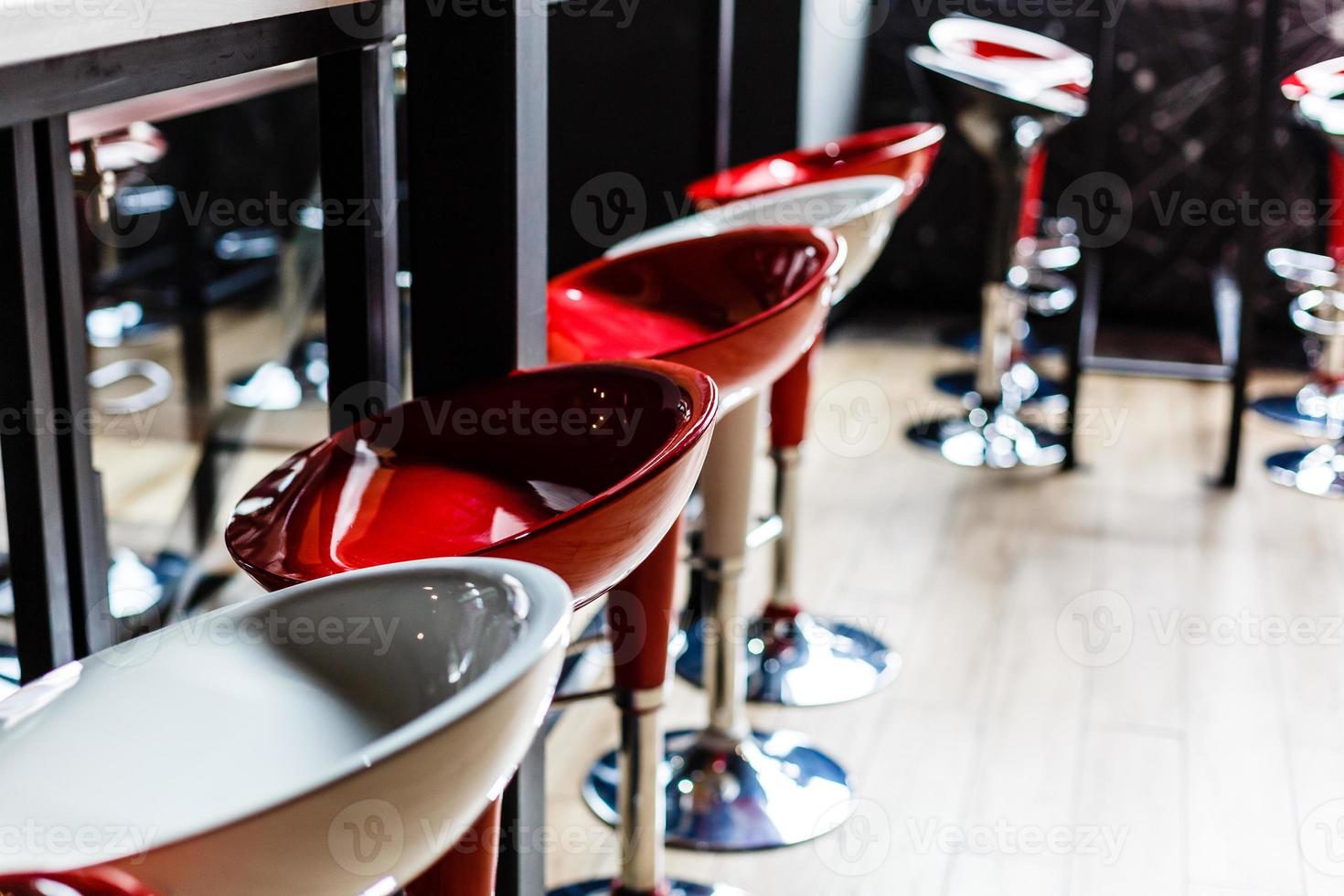 Left side of a row of red and pink square bar stools photo