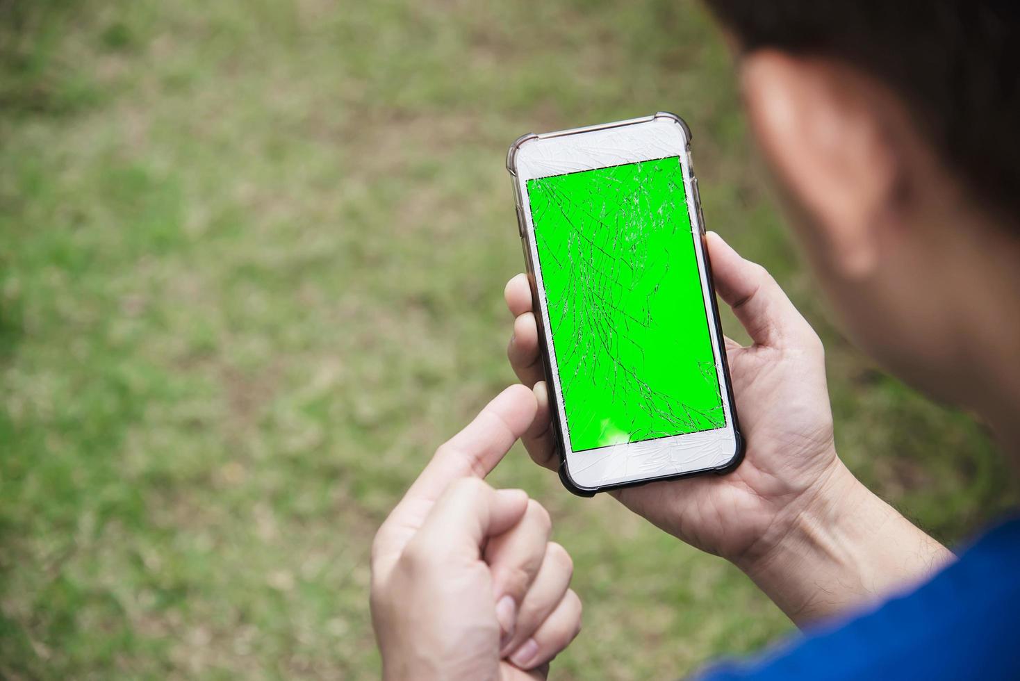 Man seriously looking at mobile phone with broken cracked screen display need to be fixed, mobile repair shop concept photo