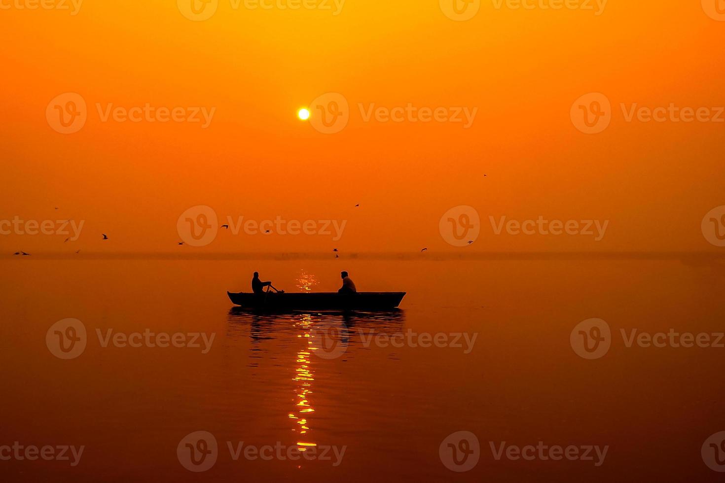 silueta de pescadores con sol amarillo y naranja en el fondo foto