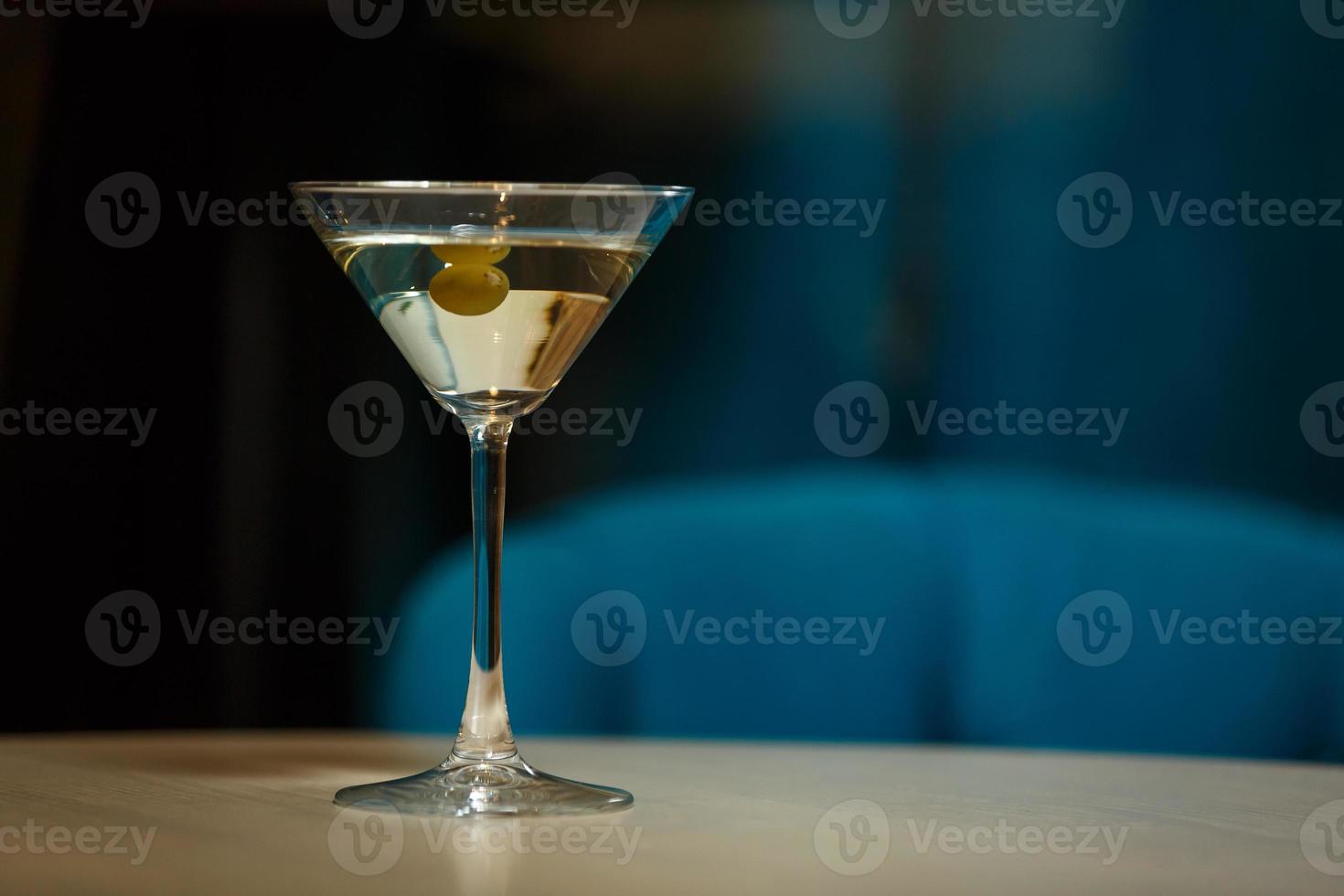 glass with martini , focus on a olives photo