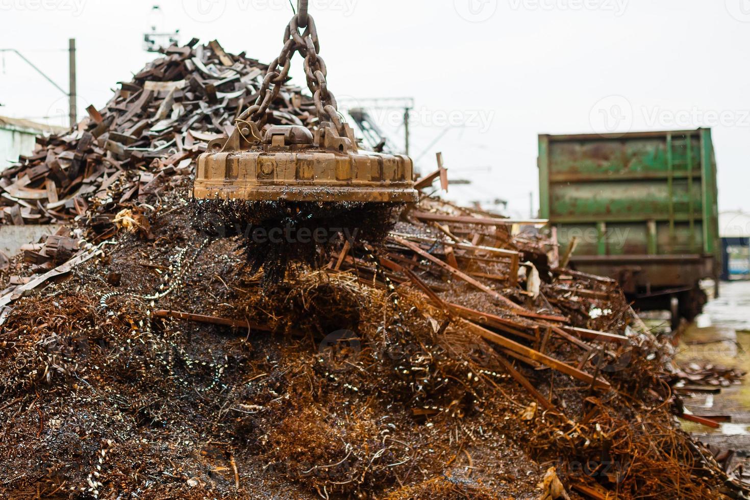 Magnetic crane loading scrap metals at junkyard photo