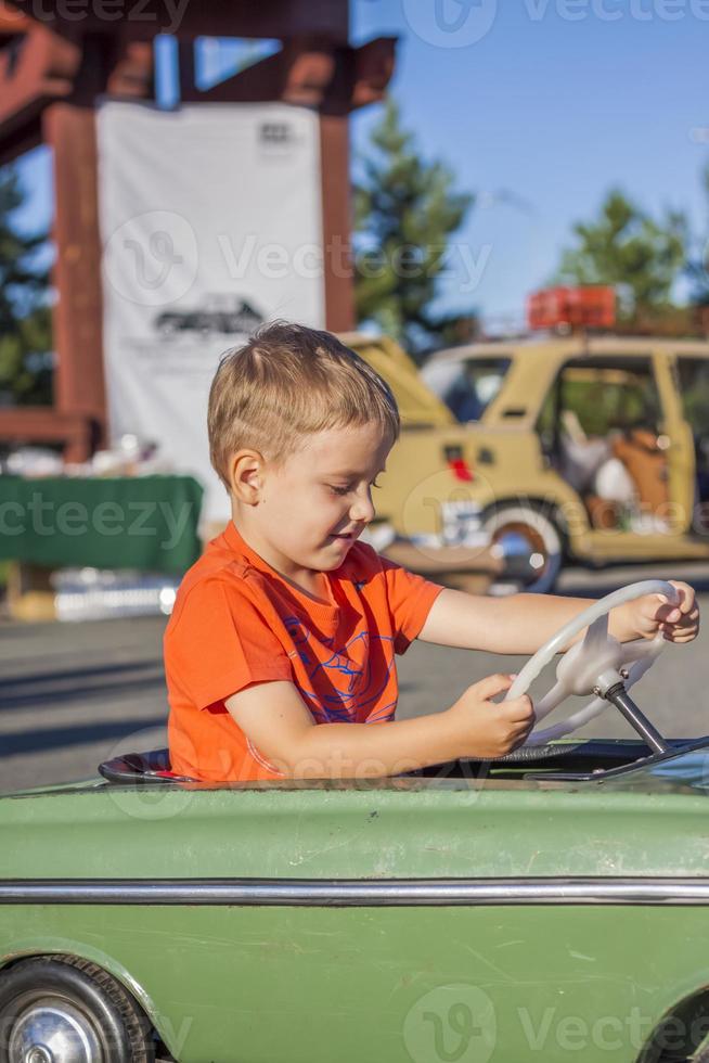 un niño conduciendo un coche para niños. emociones alegres. niños, retrato. foto