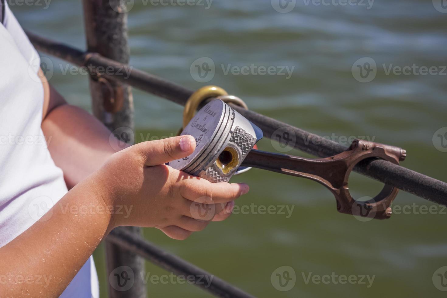 Children and a man walk across the bridge and look at the river. Various interesting things are attached to the railing. A hot summer day photo