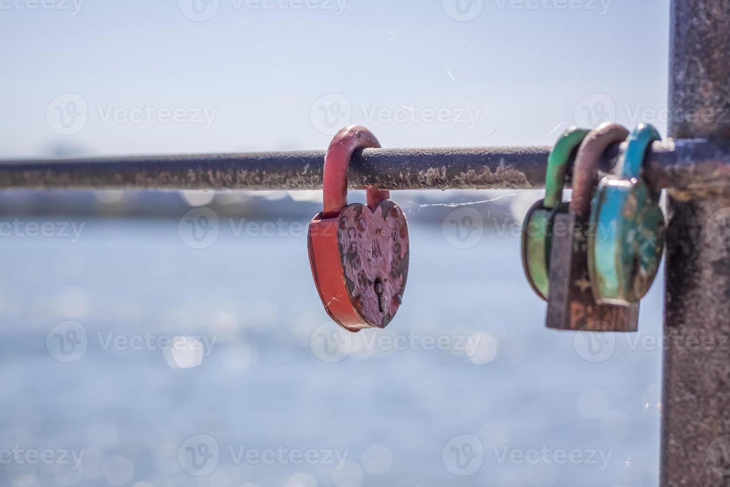 A heart-shaped door lock, a symbol of love and fidelity with a lake in the background, hangs on the fence of the bridge. The heart-shaped castle symbolizes loyalty and love photo