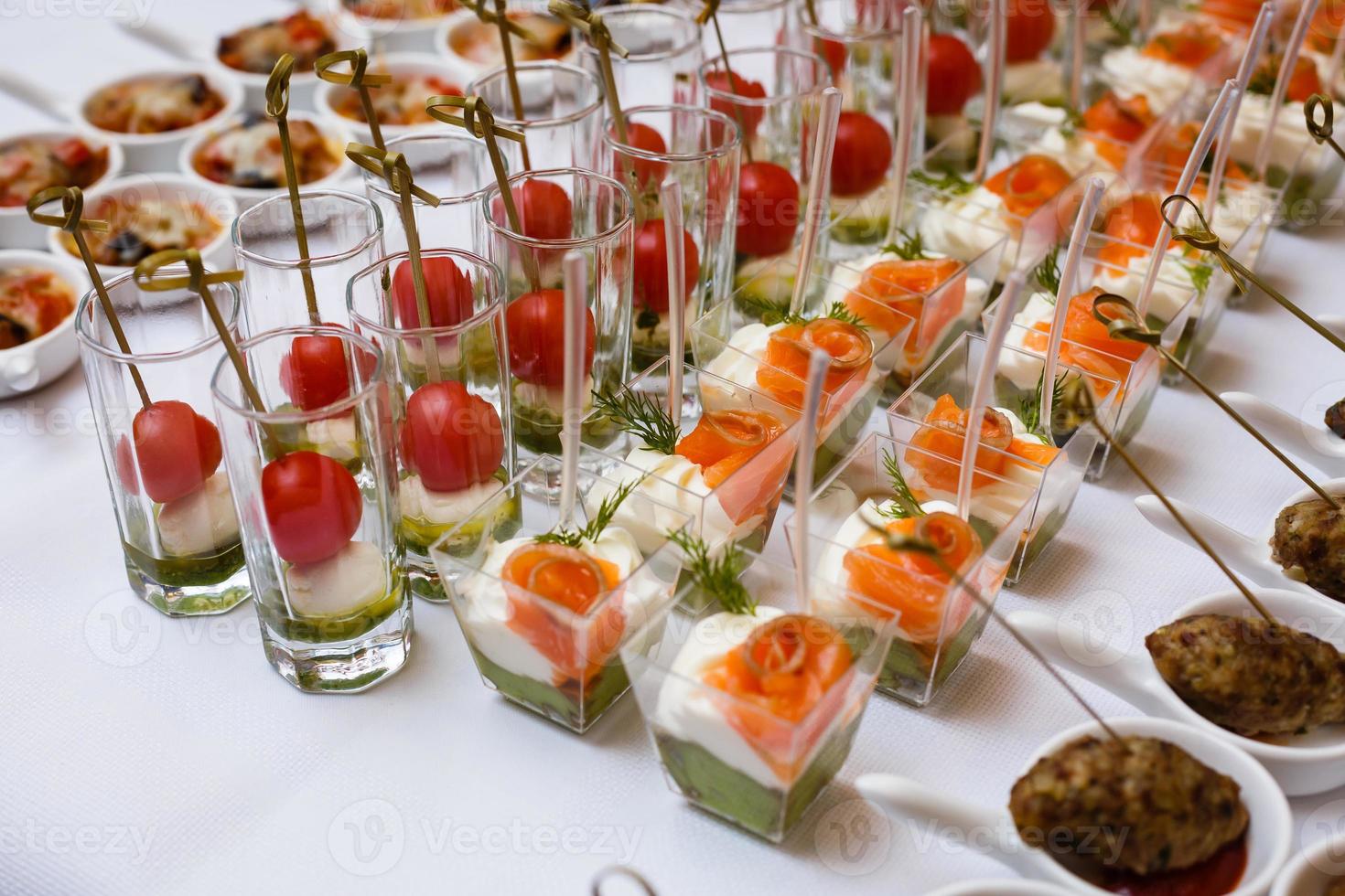 Little glasses with fresh salads stand on white table photo