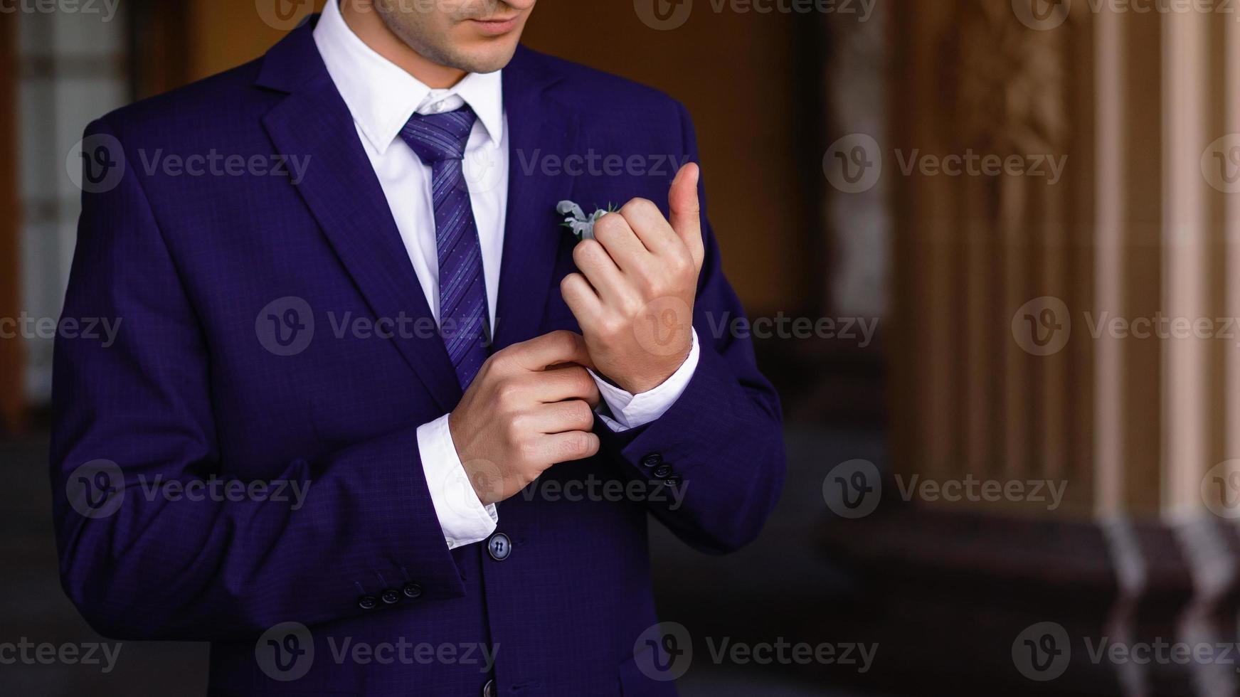 un joven con traje se endereza la corbata foto