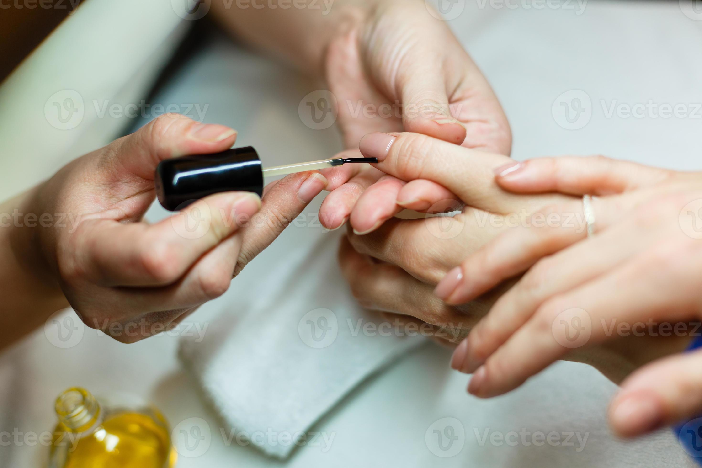 The master does a manicure in the salon, closeup. He paints his nails