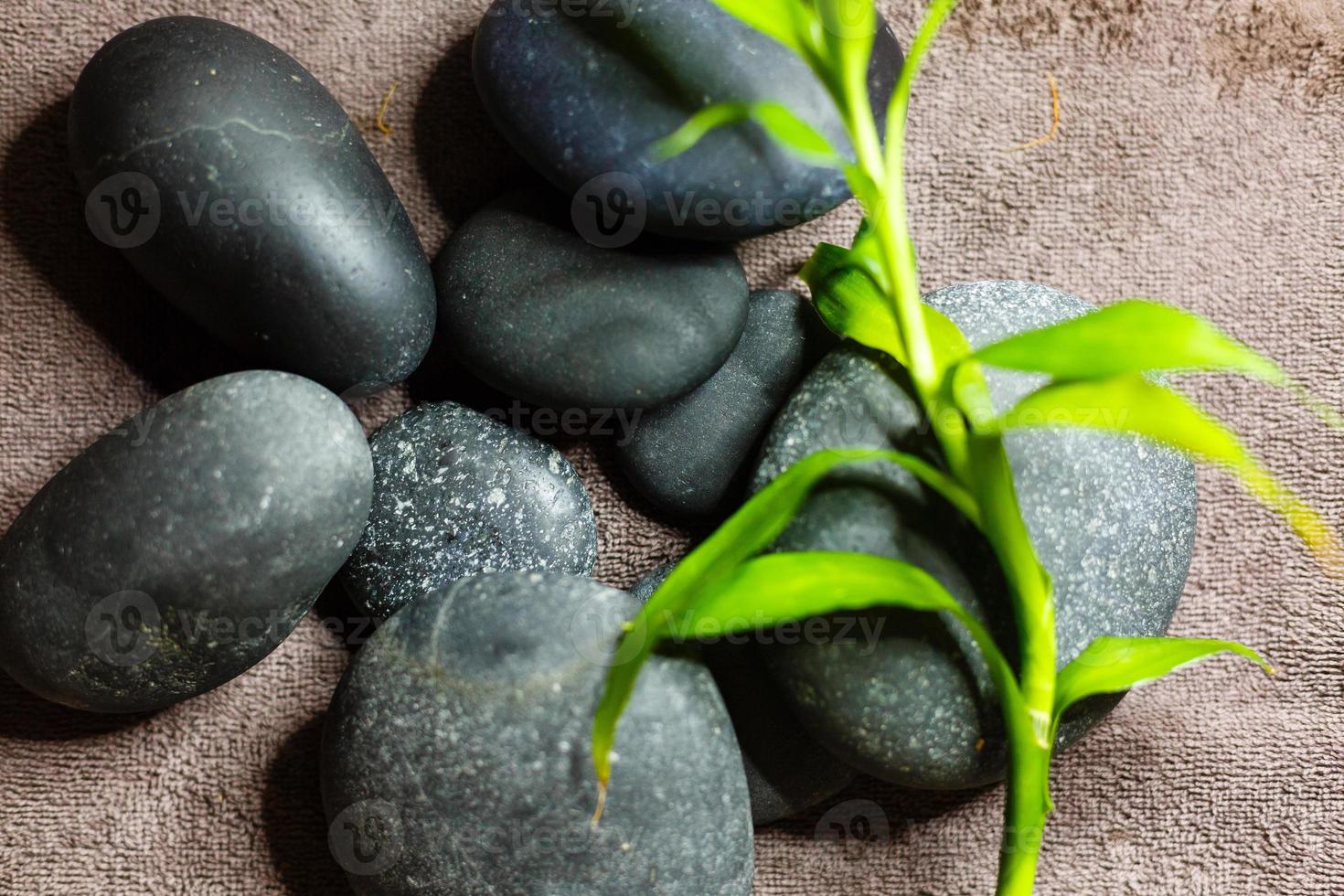 Hot spa stones with bamboo on grey background, close-up photo