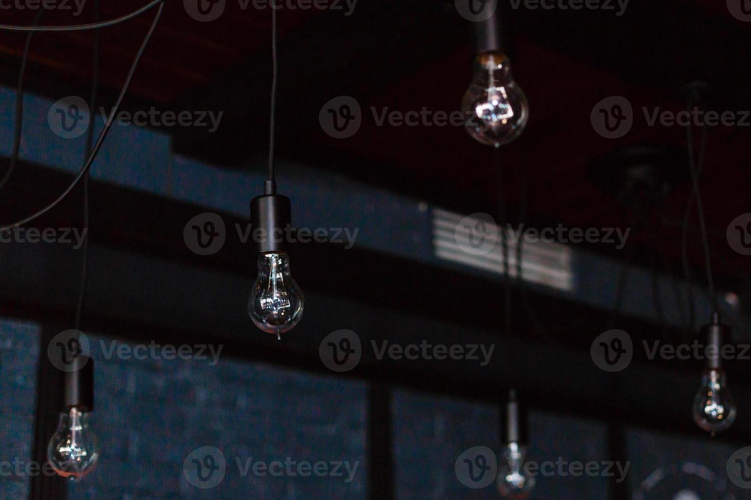 Retro light bulbs hang in interior with white brick wall background. light bulbs hanging on brick wall backdrop photo