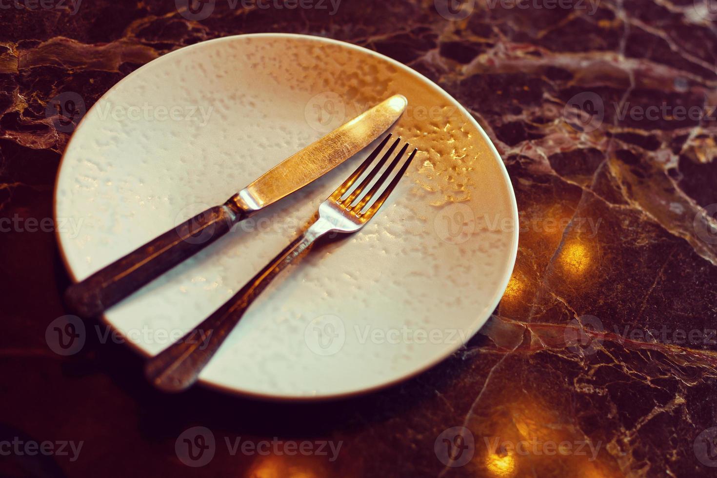 Empty plate with knife and fork on vintage wooden table photo