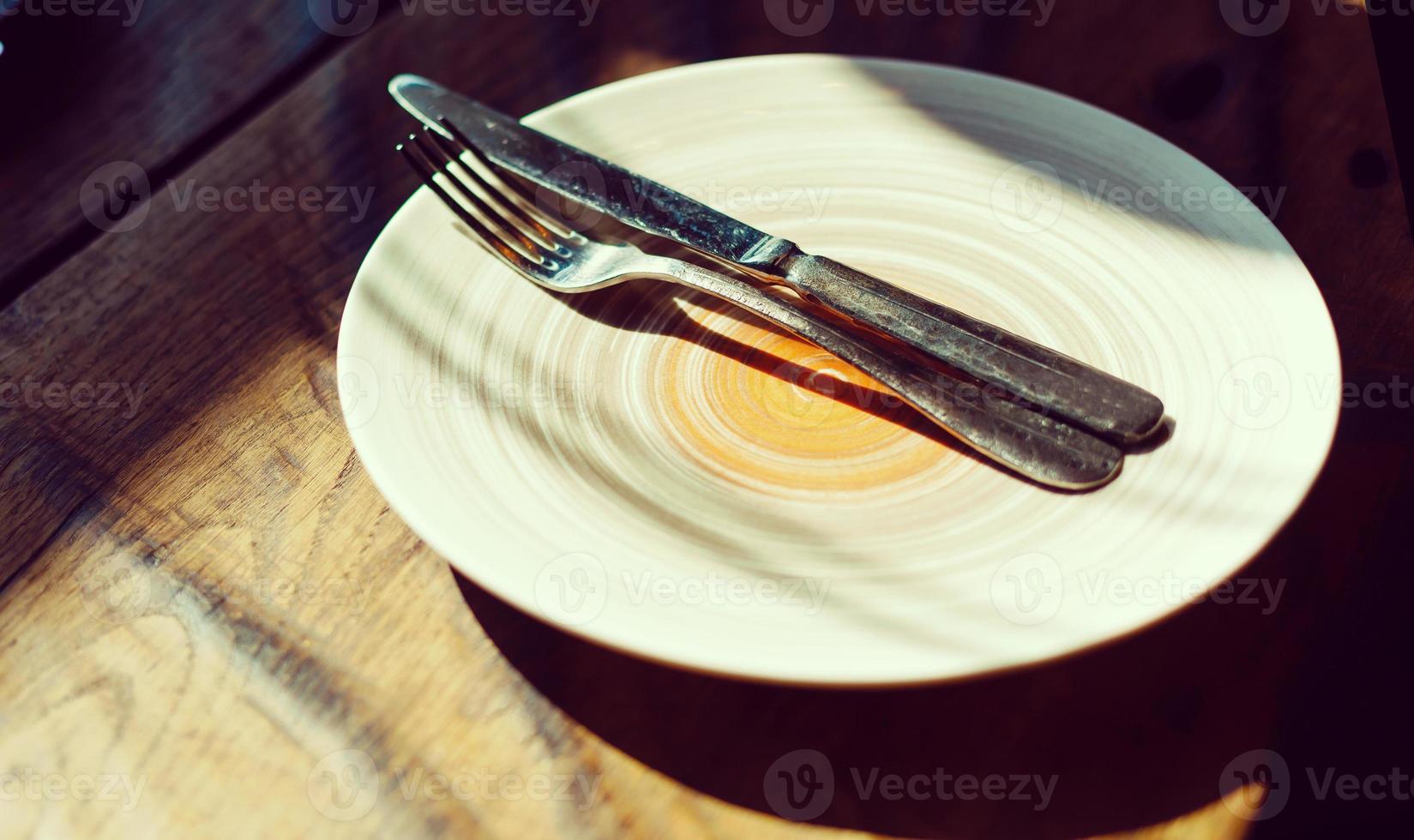 plato vacío con cuchillo y tenedor en una mesa de madera antigua foto
