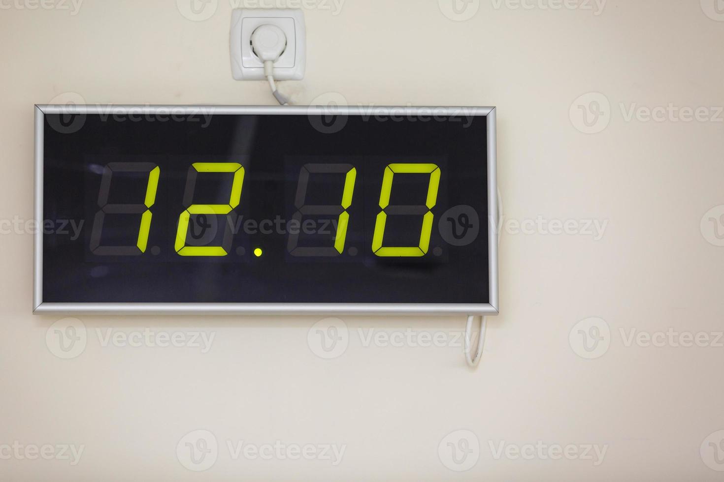 Black digital clock on a white background showing time twelve hours ten minutes photo