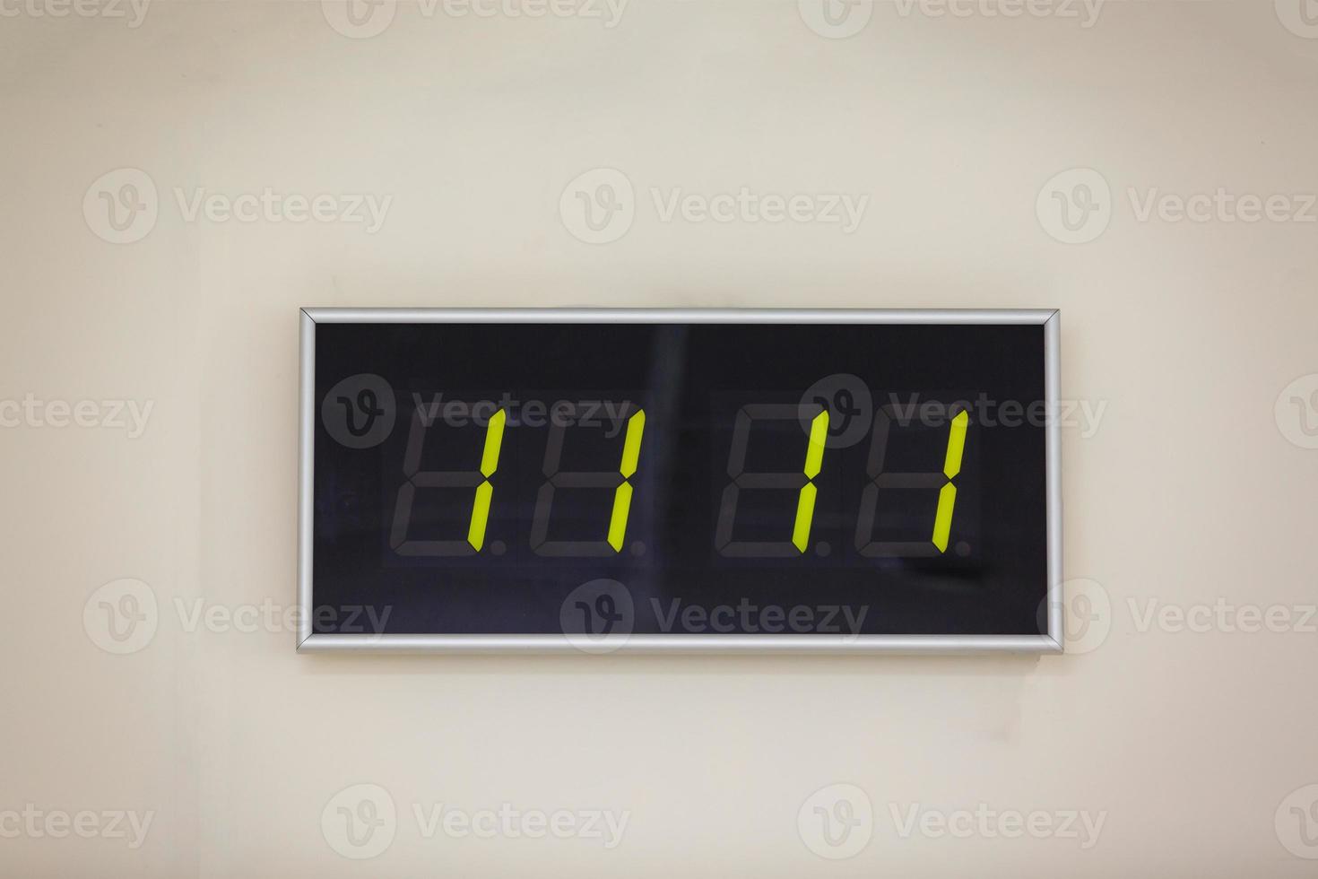 reloj digital negro sobre un fondo blanco que muestra la hora once horas once minutos foto