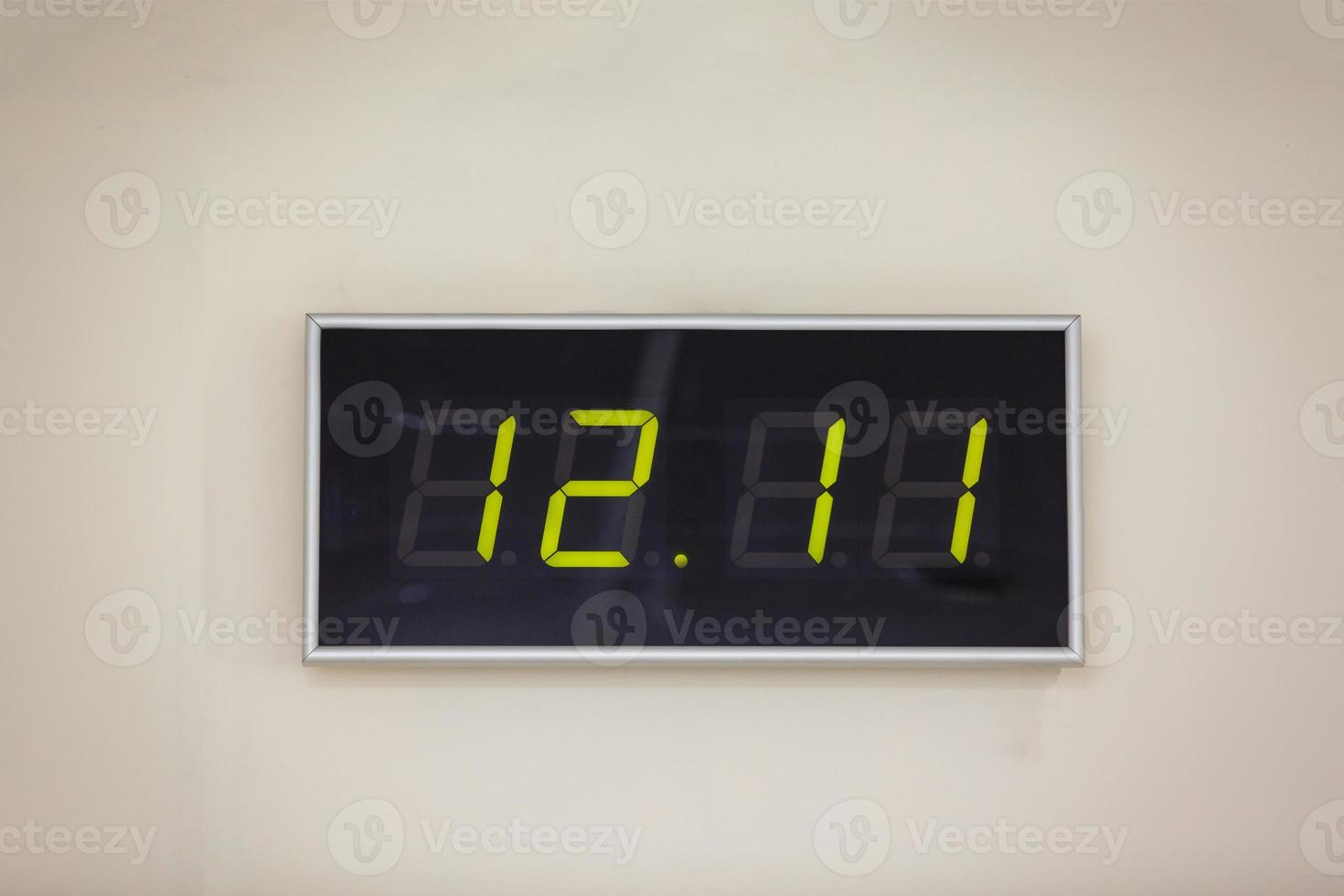 reloj digital negro sobre un fondo blanco que muestra la hora doce horas once minutos foto