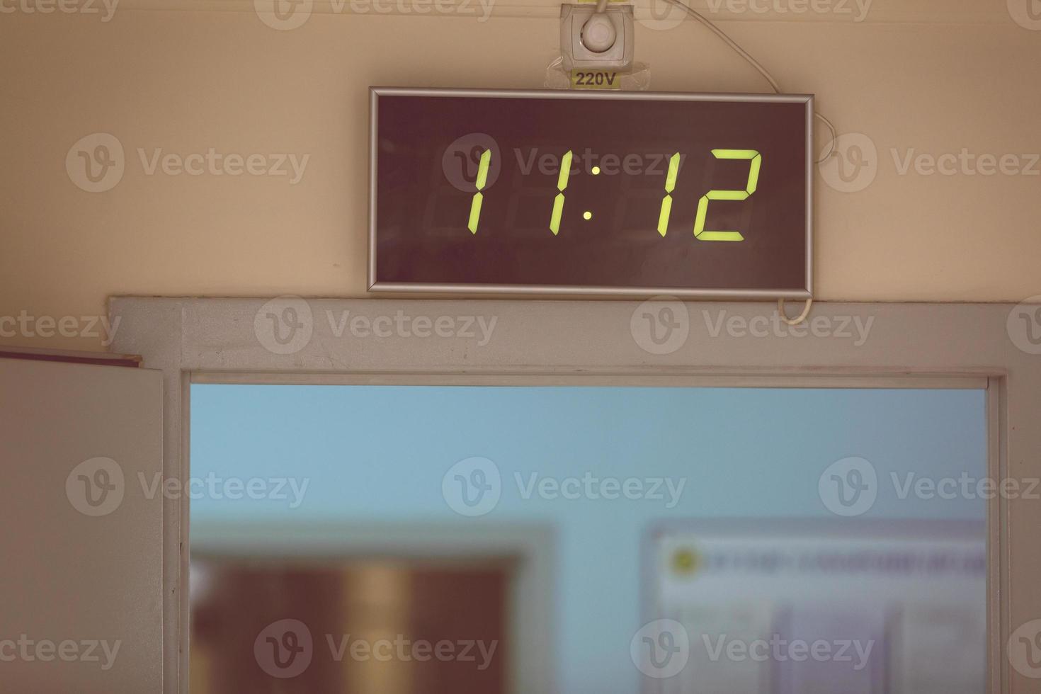 reloj digital negro sobre un fondo blanco que muestra la hora once horas doce minutos foto