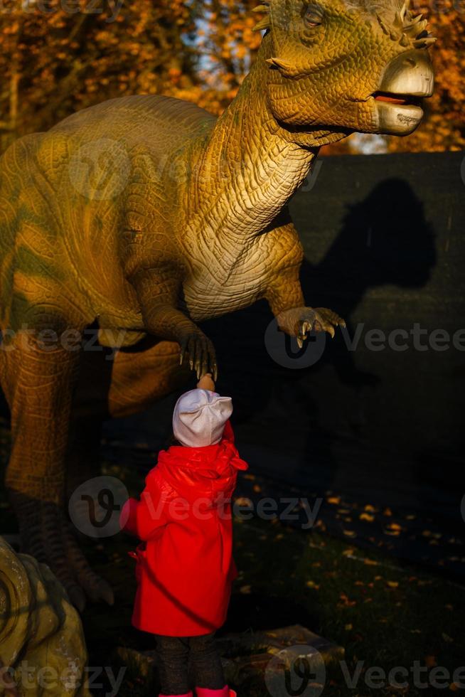 little girl in a park of dinosaurs photo