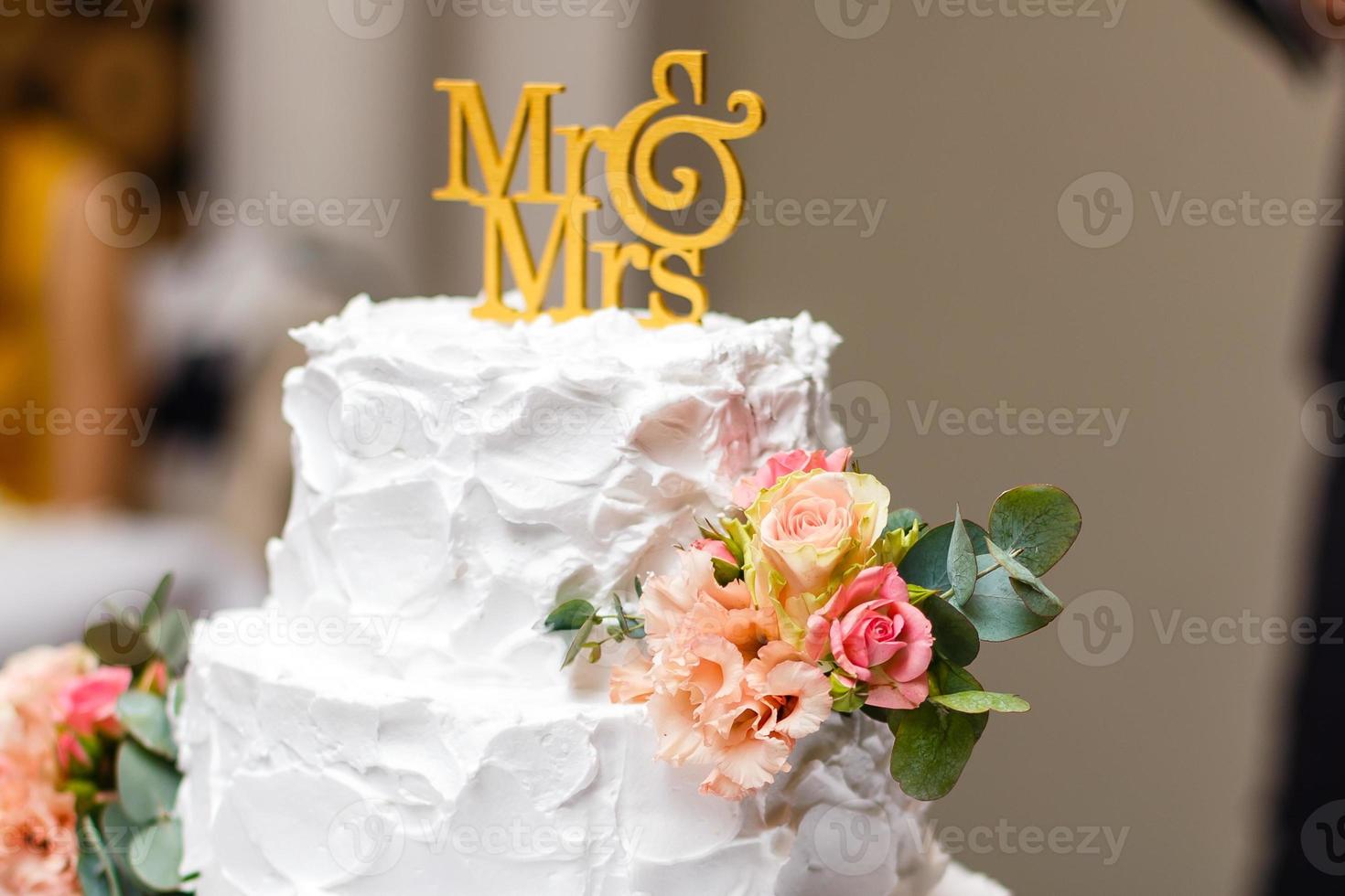 un pastel de bodas blanco de varios niveles sobre una base plateada y flores rosas en la parte superior foto