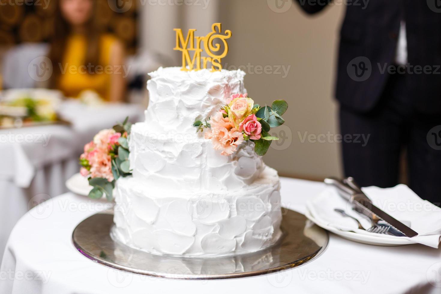 a multi level white wedding cake on a silver base and pink flowers on top photo