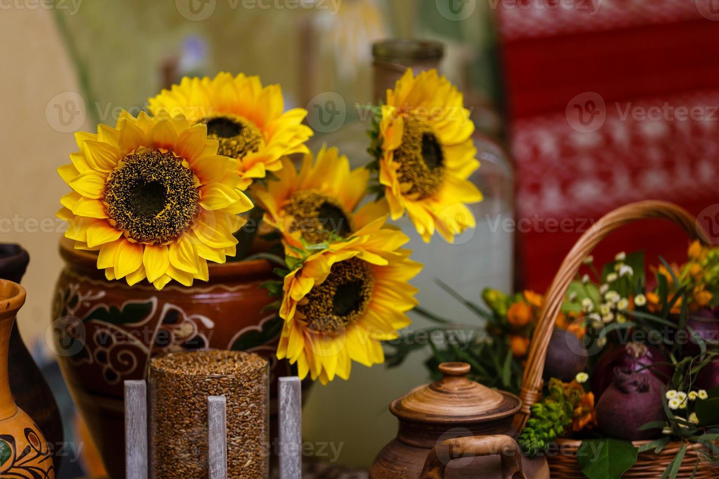 Bouquet of sunflowers in old clay jug. In the foreground branches with ripe cherry plum photo