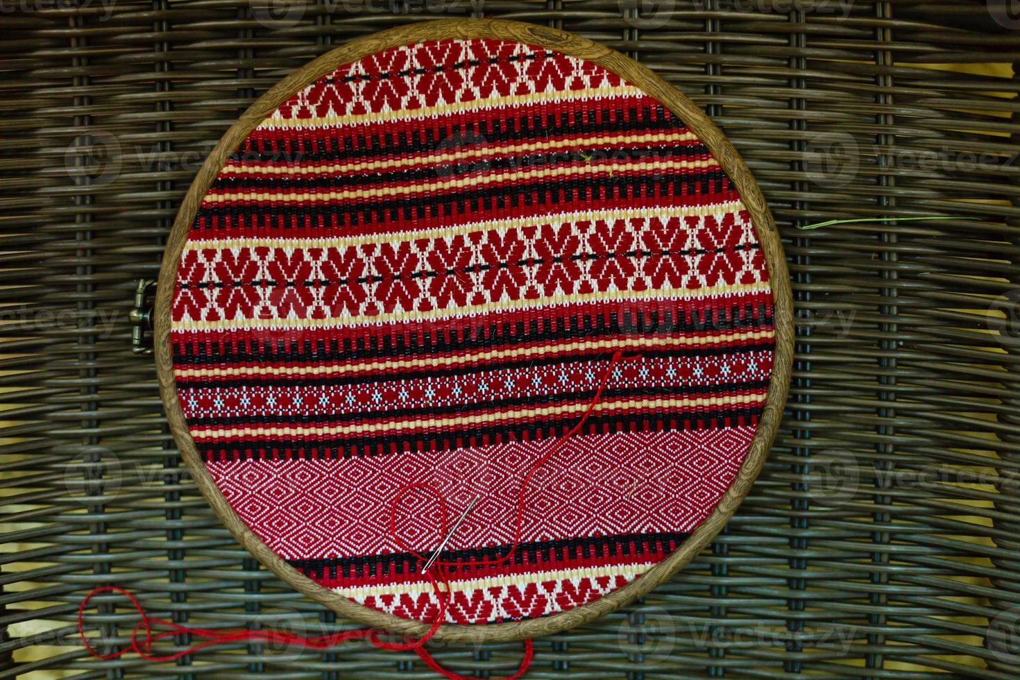 The wooden hoop with the embroidery pattern of red and Black color on canvas. Slavic Embroidery with hemming. photo