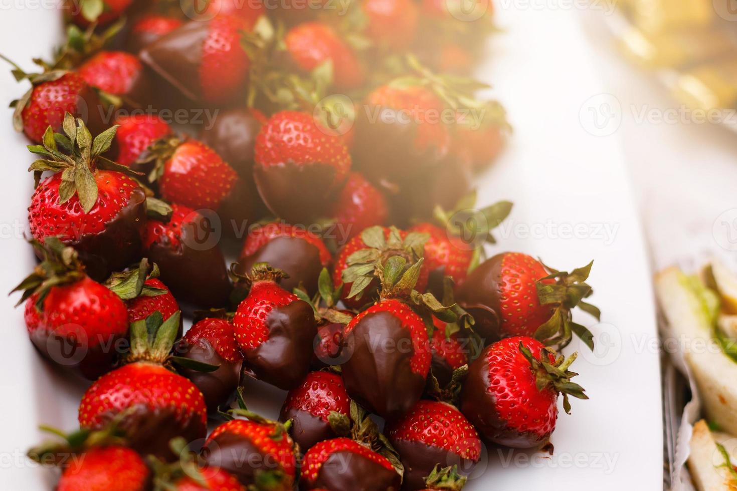 Fresh strawberries dipped in dark chocolate on blue wooden background photo