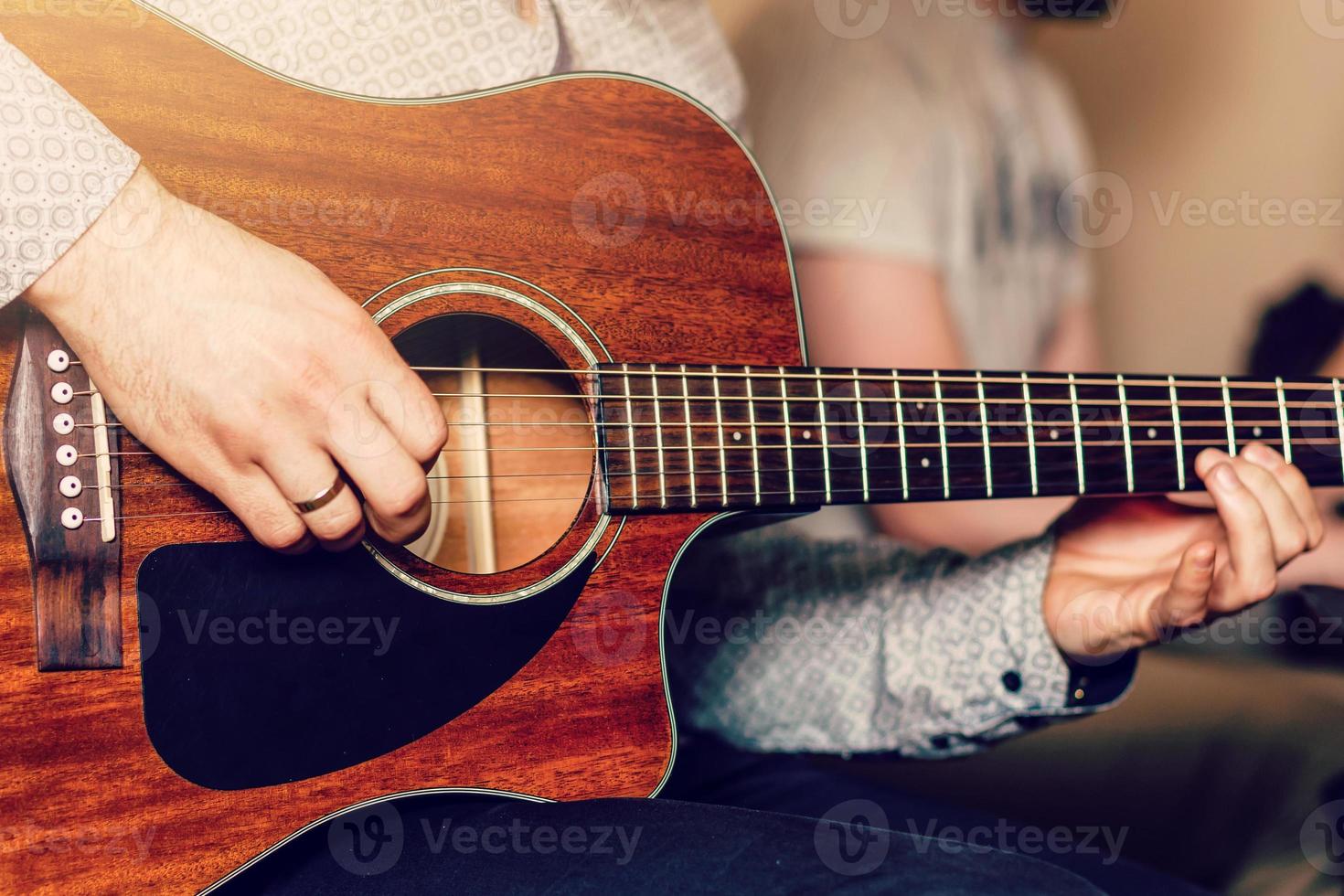 joven músico tocando la guitarra acústica de cerca foto