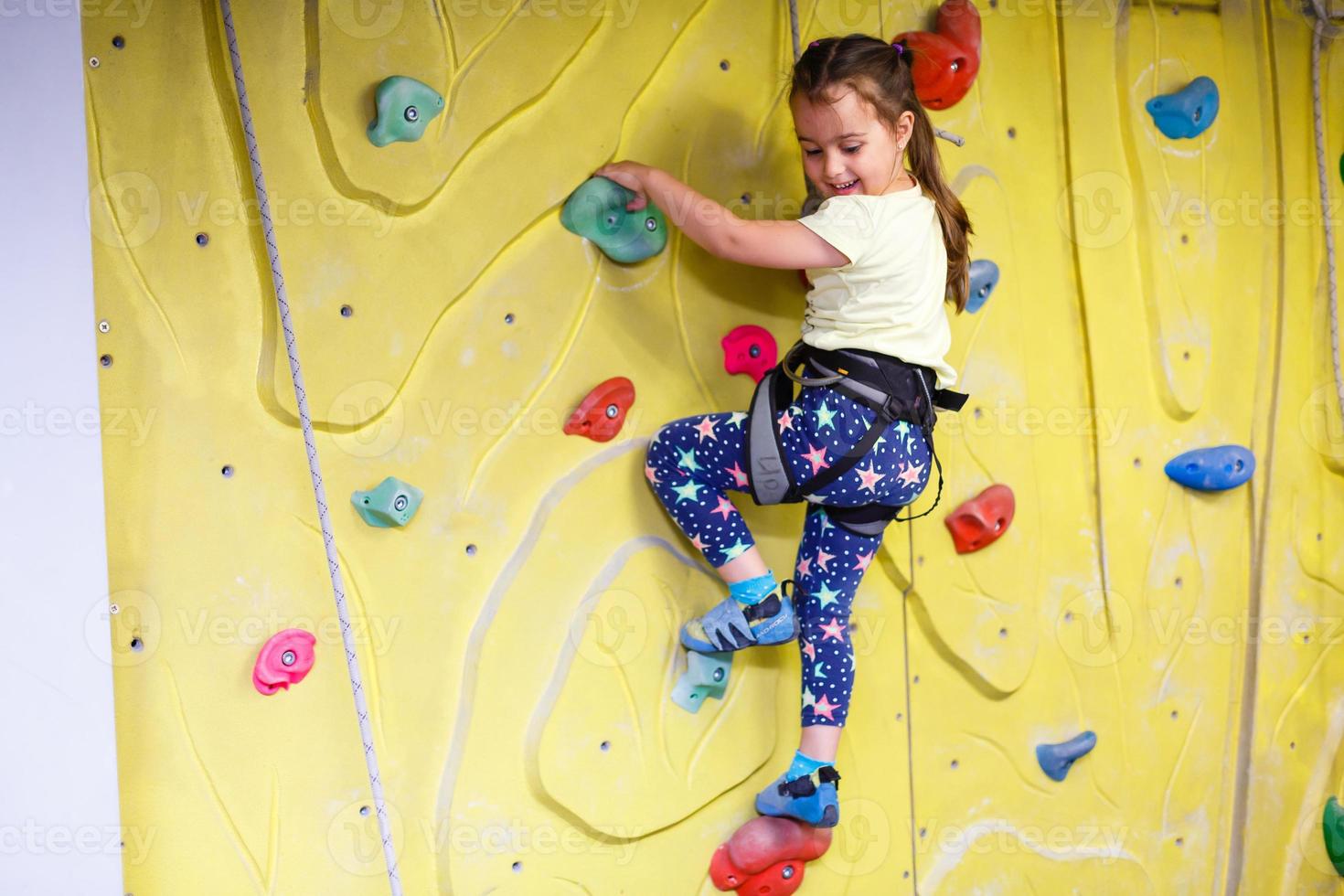 little girl climbing a rock wall indoor photo