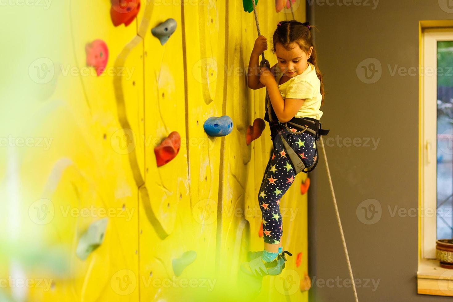 niña escalando una pared de roca interior foto