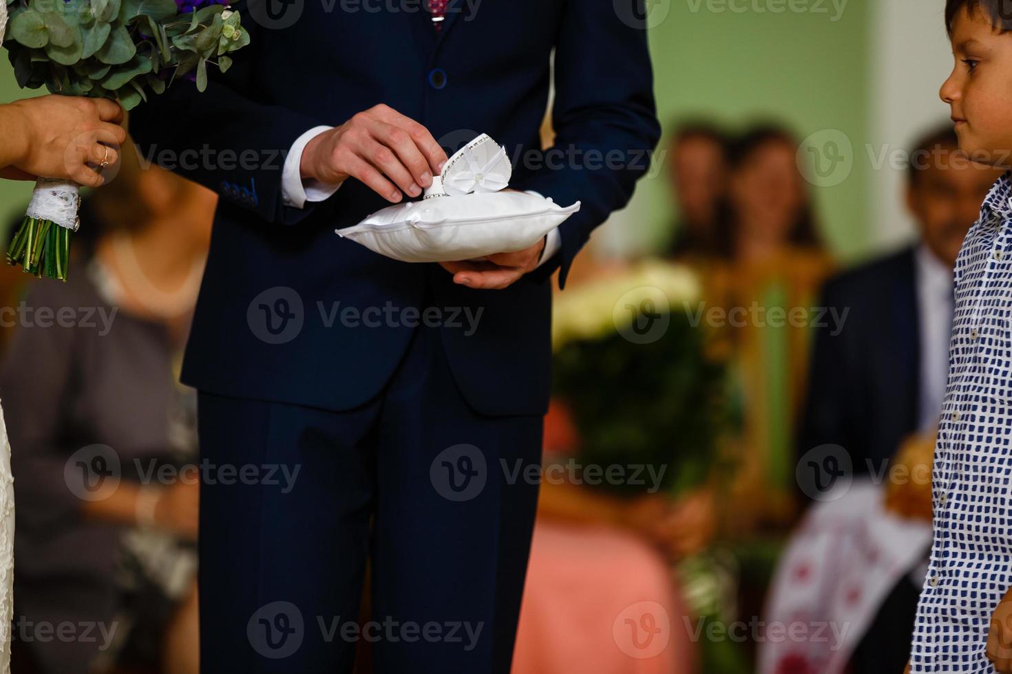 Bride taking ring from silk cushion at wedding ceremony photo