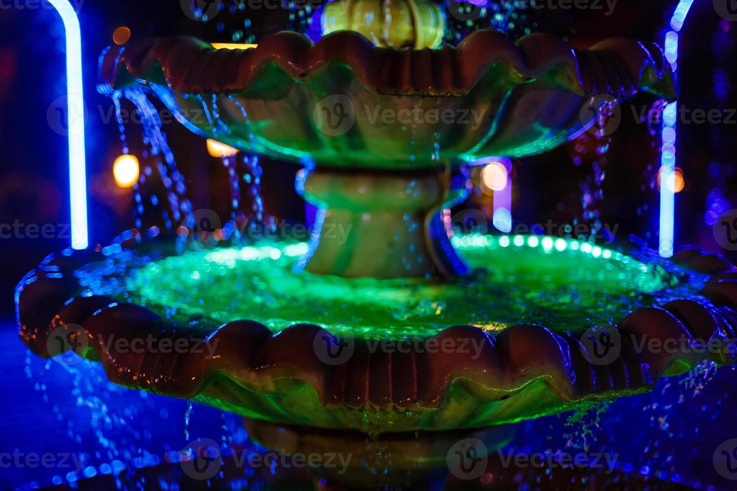 small fountain with blue and yellow color illumination in the park photo