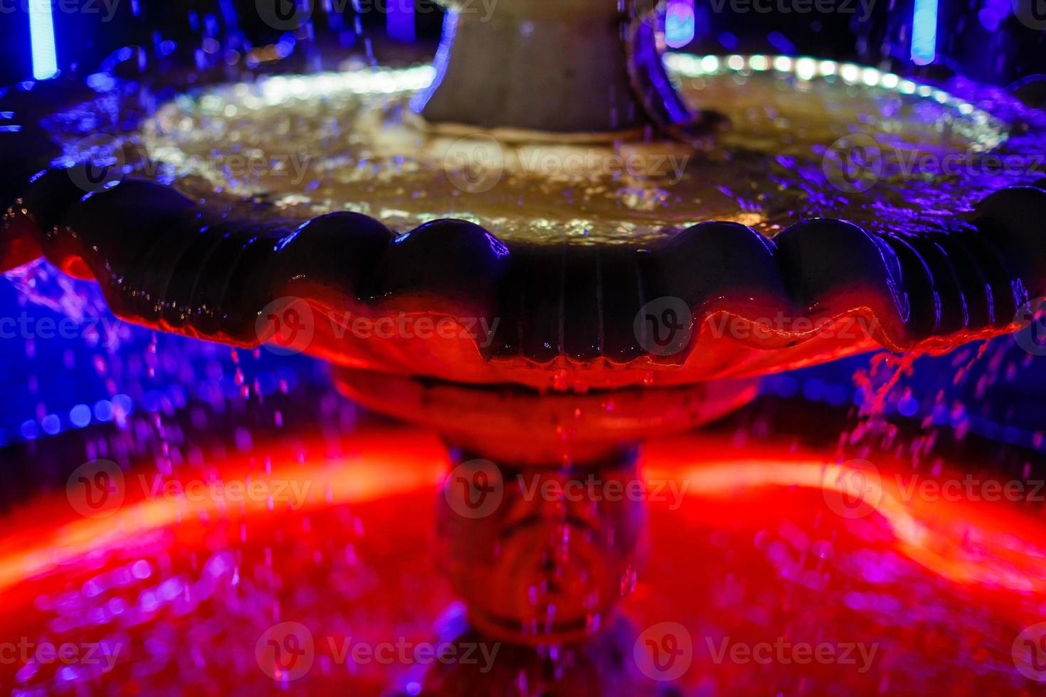 small fountain with blue and yellow color illumination in the park photo