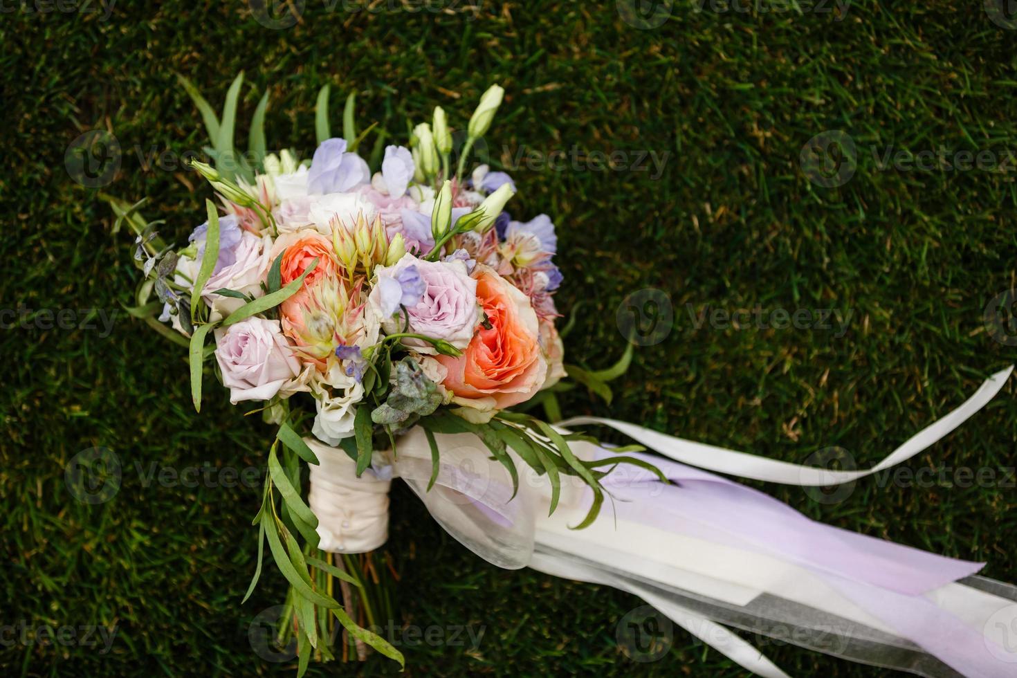 Bridal bouquet. The bride's bouquet. Bouquet of white, pink and green colors with silk ribbons of pastel color on grass background photo