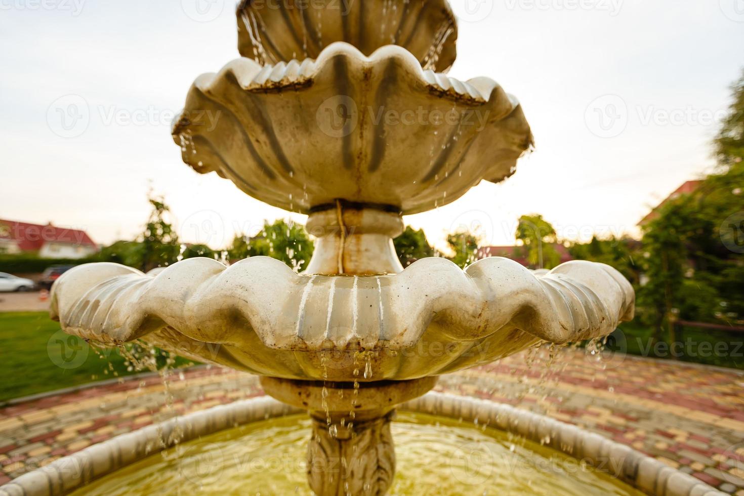 Close up on water dripping out of stone fountain in beautiful spring flower garden. Shallow Depth of Field. photo