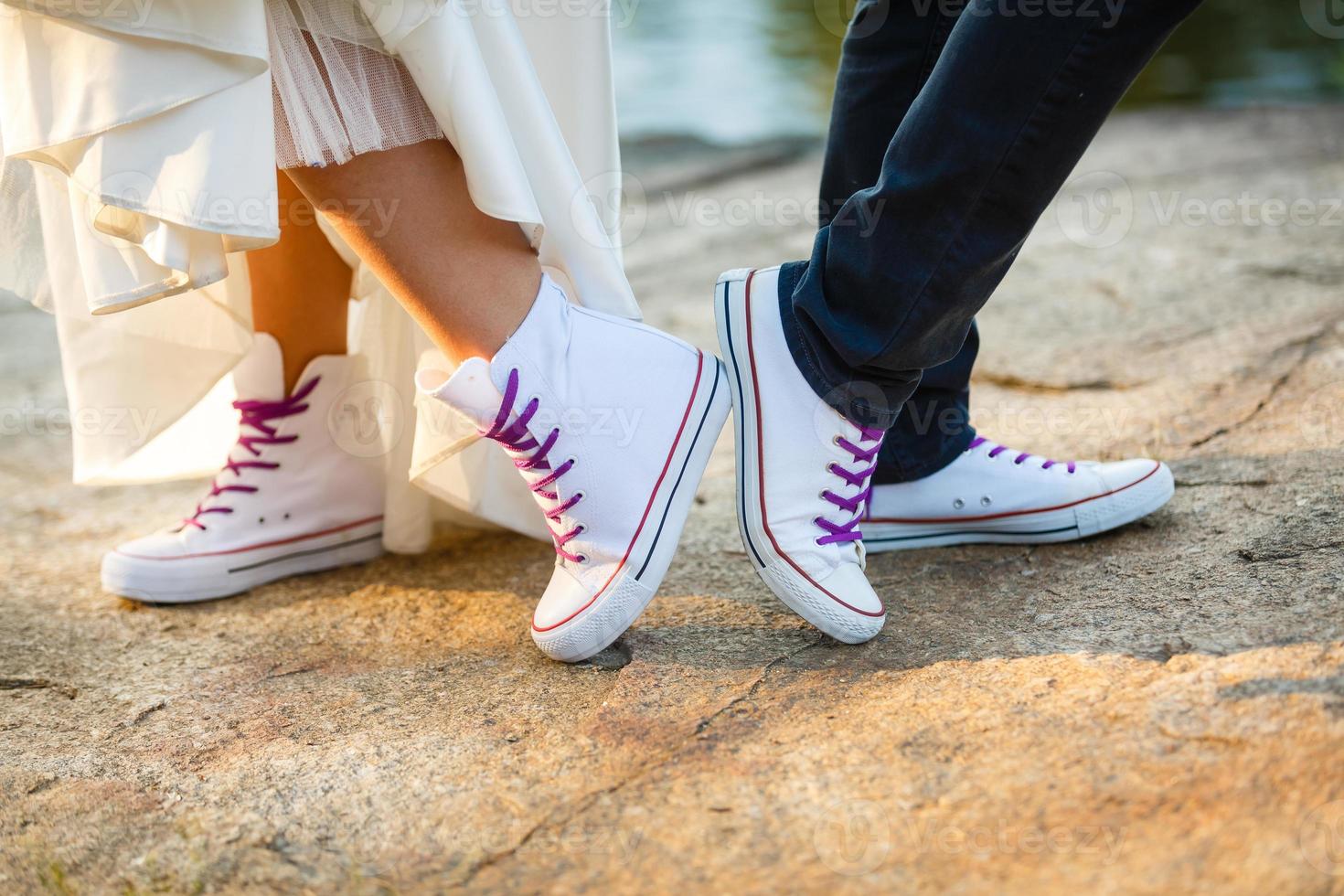 Love story told by boots. Human feet close up. Man and woman in sneakers. Girl in white shoes. Guy in black sneakers and denim. Hipster couple in summer. Legs close up. photo