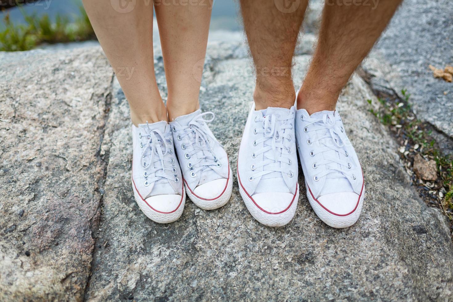 historia de amor contada por botas. pies humanos de cerca. hombre y mujer en zapatillas. chica con zapatos blancos. chico con zapatillas negras y denim. pareja hipster en verano. las piernas se cierran. foto