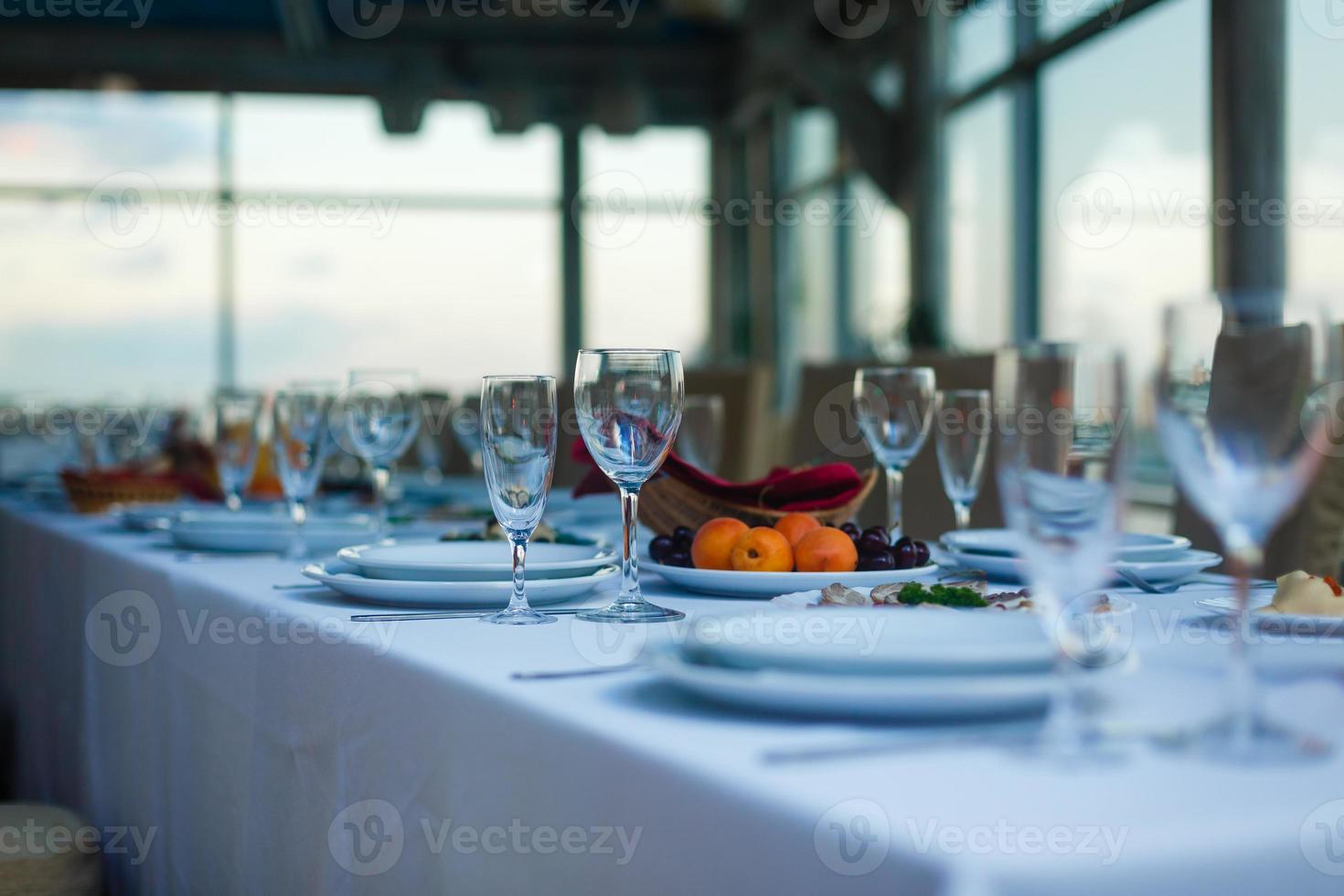 Sparkling glassware stands on long table prepared for wedding dinner photo