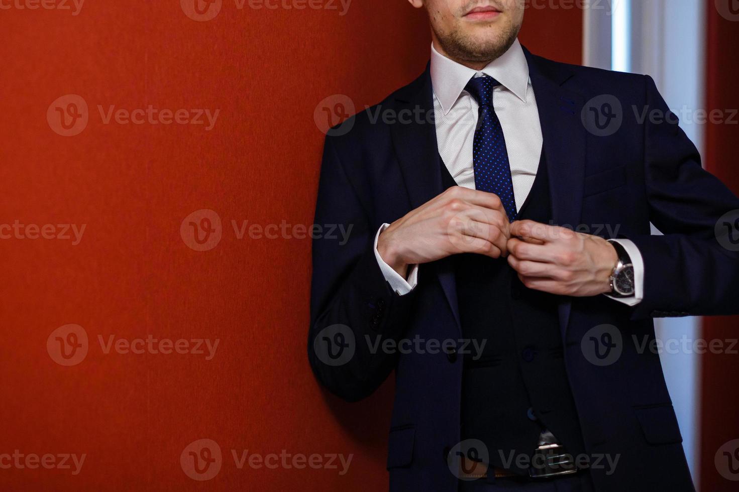 Man on red background adjusts suit photo
