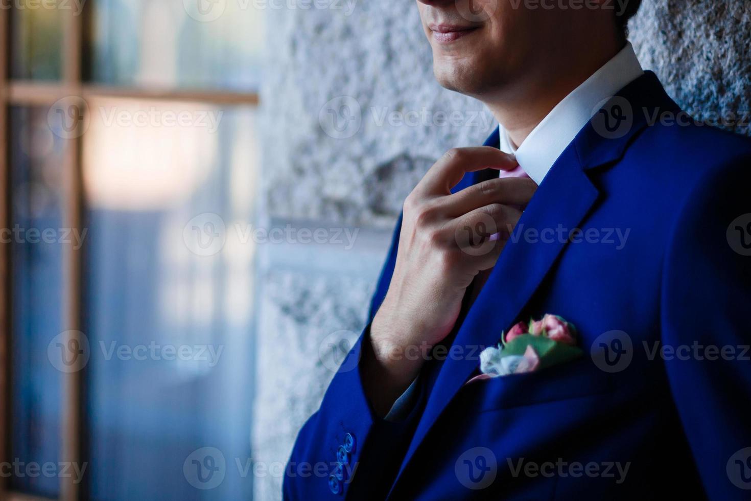 elegante traje azul de hombre de negocios, endereza su corbata en un hotel caro, yendo a una reunión foto