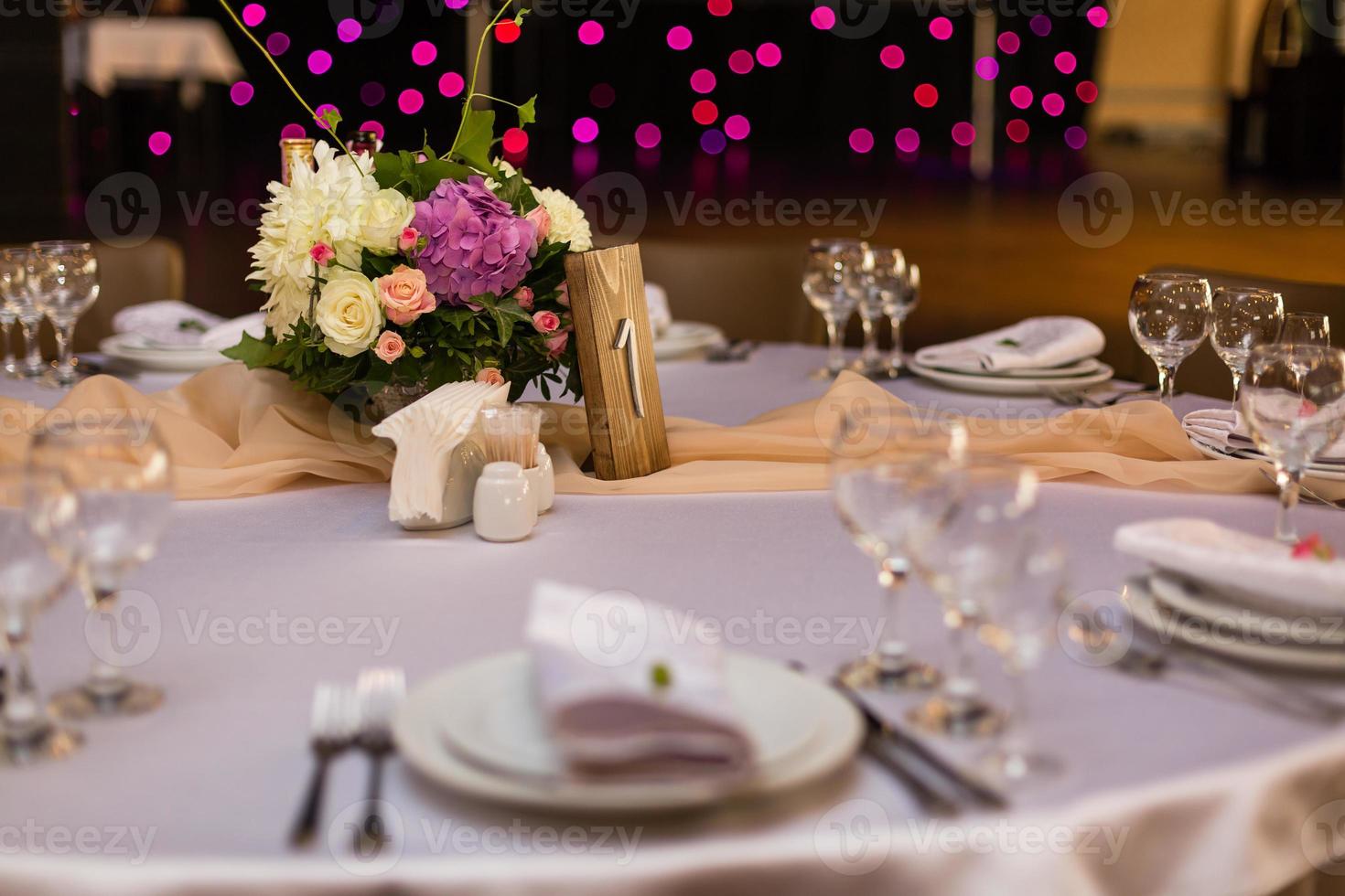 Beautiful table setting with crockery and flowers for a party, wedding reception or other festive event. Glassware and cutlery for catered event dinner. photo