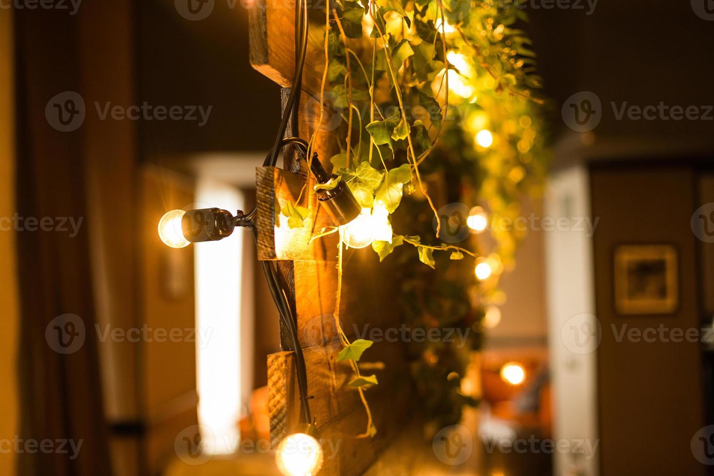 Wooden natural garland decorated with bulb lights on wedding ceremony. Dim light photo