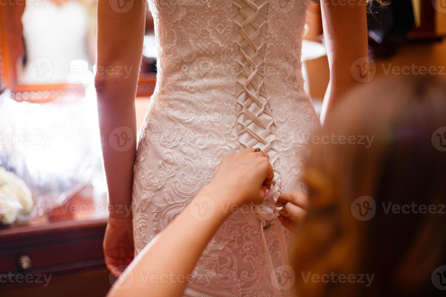 bridesmaid tying bow on wedding dress photo